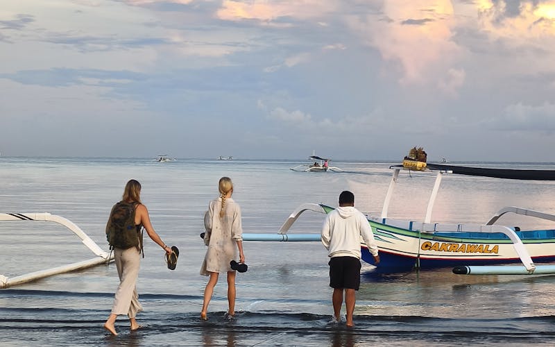 Tourists boarding a traditional boat at sunrise in Bali